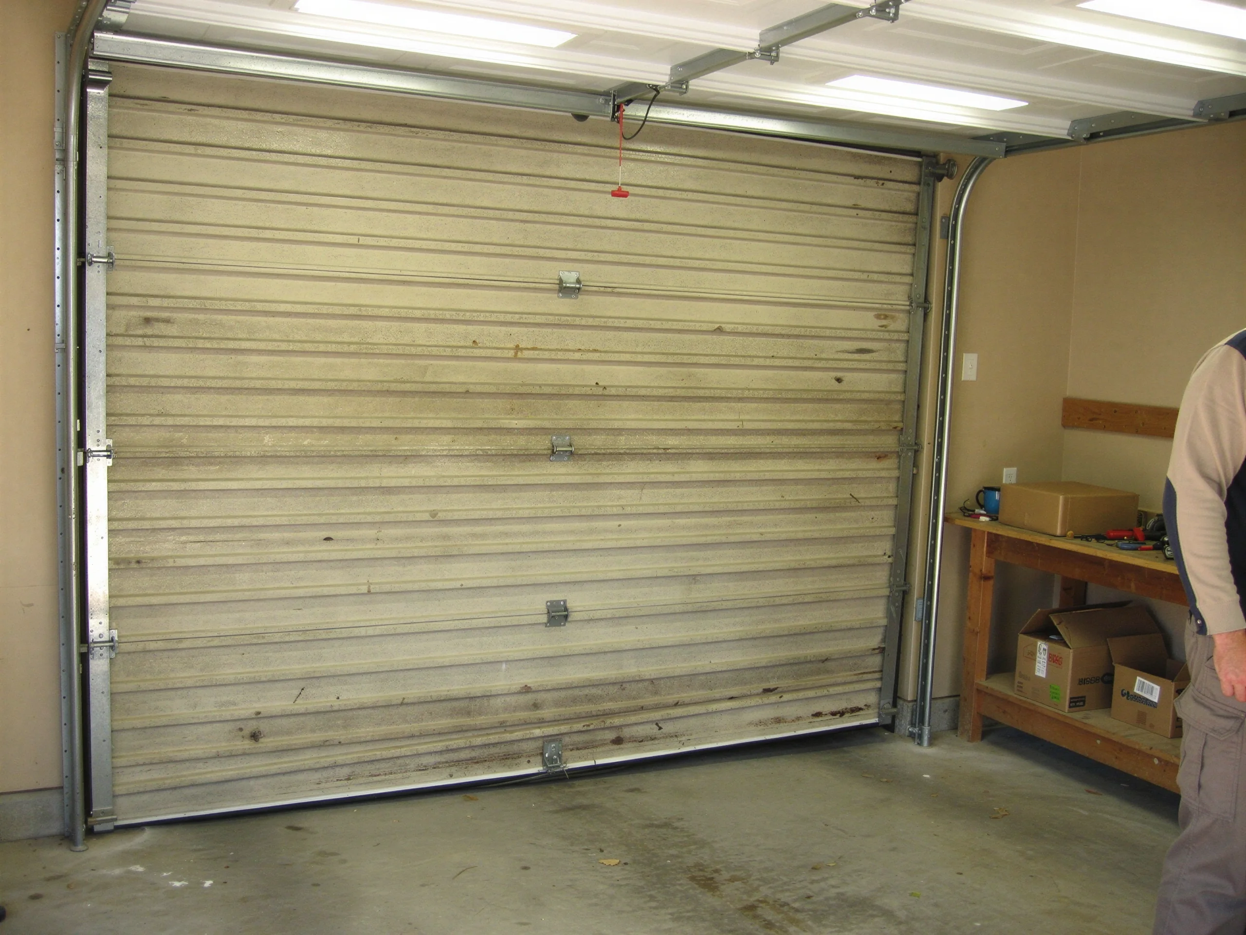A dirty, closed garage door is visible from inside a garage.